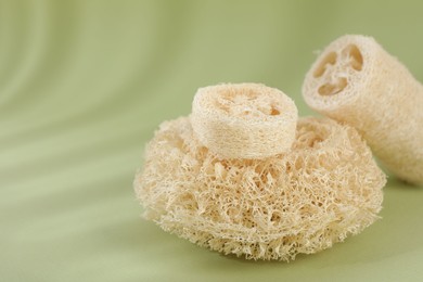 Photo of Different loofah sponges on olive background, closeup. Space for text