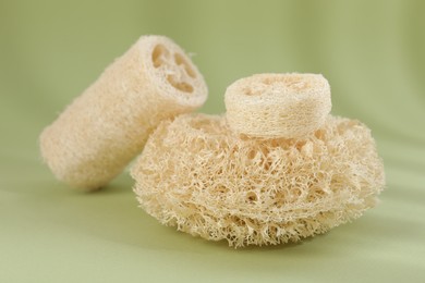 Photo of Different loofah sponges on olive background, closeup
