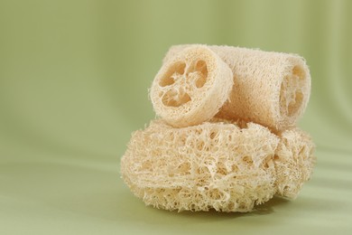 Photo of Different loofah sponges on olive background, closeup. Space for text