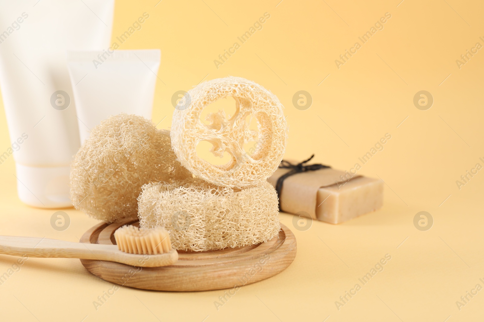 Loofah sponges, toothbrush, tubes of cosmetic product and soap on beige background, closeup. Space for text Photo of Loofah sponges, toothbrush, tubes of cosmetic product and soap on beige background, closeup. Space for text