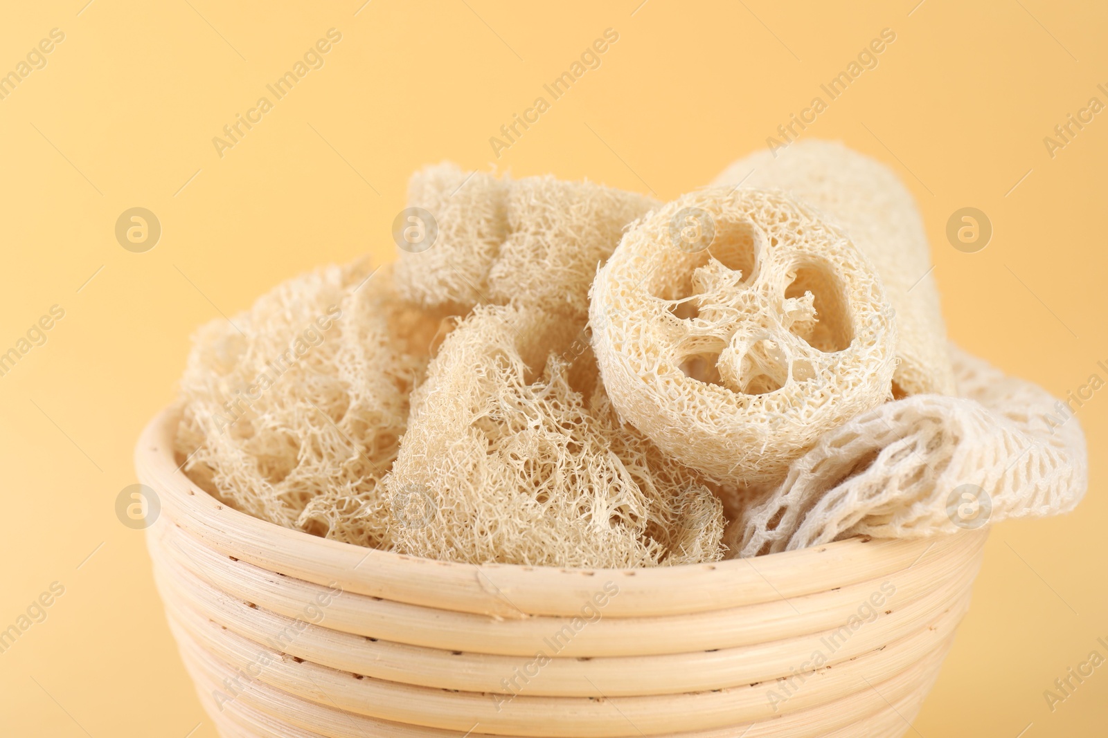 Different loofah sponges in bowl on beige background, closeup Photo of Different loofah sponges in bowl on beige background, closeup