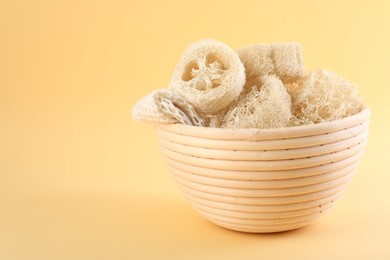 Photo of Different loofah sponges in bowl on beige background, closeup. Space for text