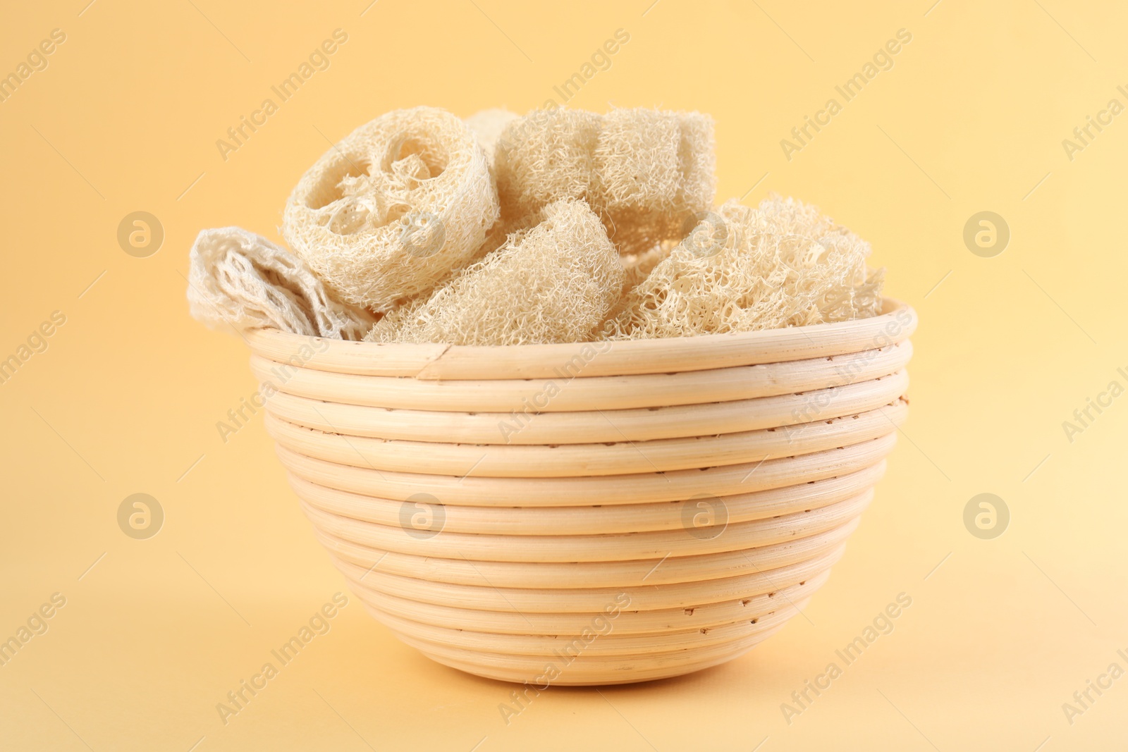 Different loofah sponges in bowl on beige background, closeup Photo of Different loofah sponges in bowl on beige background, closeup