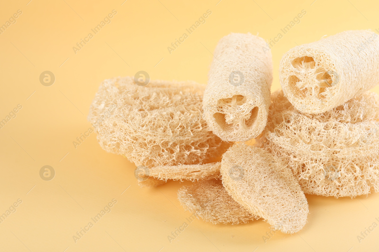 Different loofah sponges on beige background, closeup. Space for text Photo of Different loofah sponges on beige background, closeup. Space for text