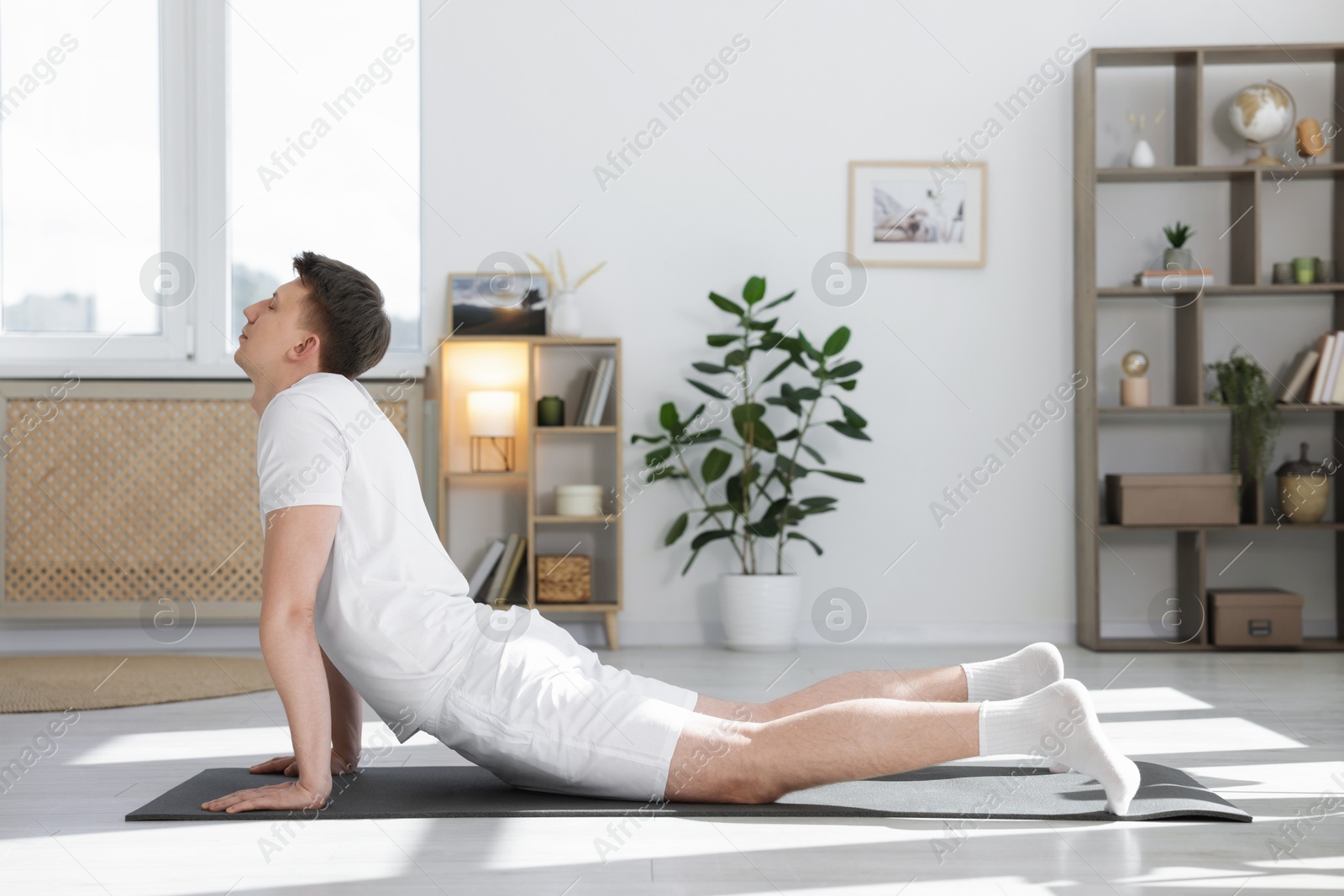 Young man practicing yoga on mat at home. Space for text Photo of Young man practicing yoga on mat at home. Space for text