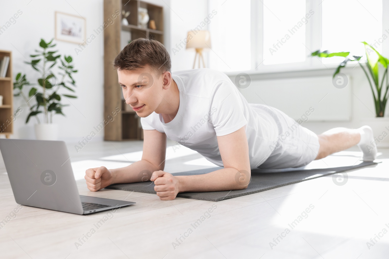 Man having online yoga class via laptop at home Photo of Man having online yoga class via laptop at home