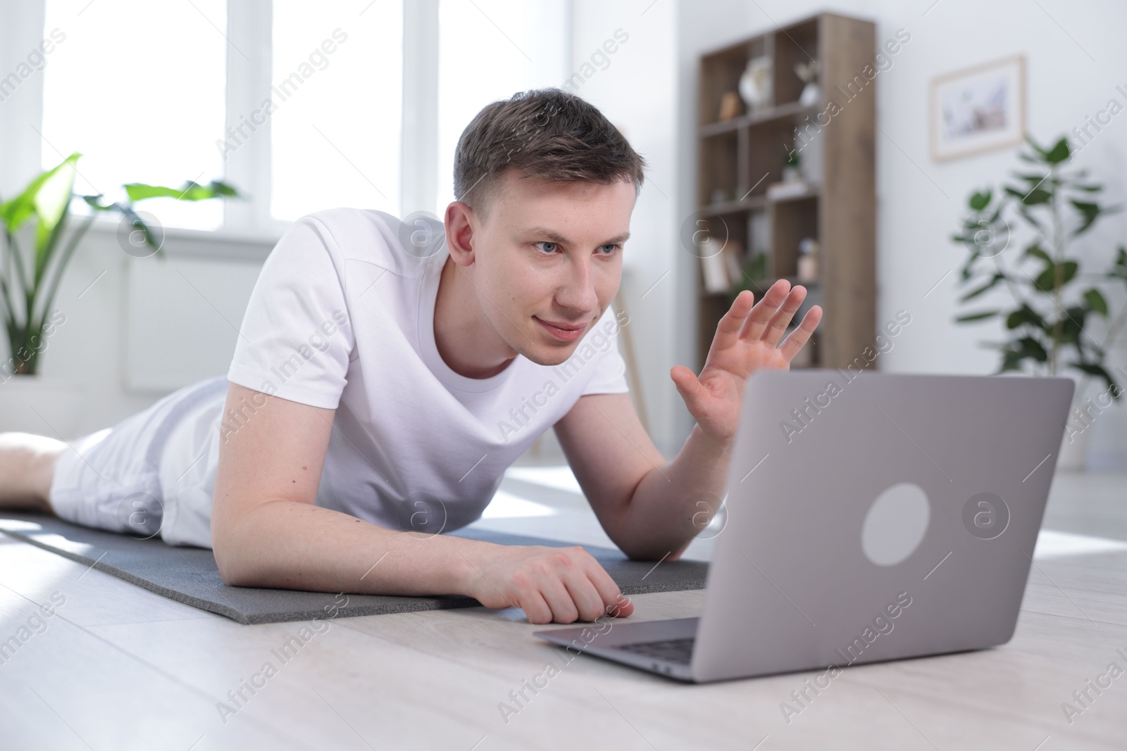 Man having online yoga class via laptop at home Photo of Man having online yoga class via laptop at home