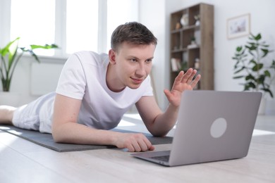 Photo of Man having online yoga class via laptop at home