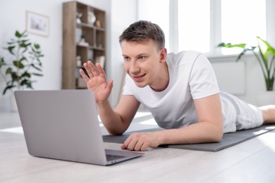 Photo of Man having online yoga class via laptop at home