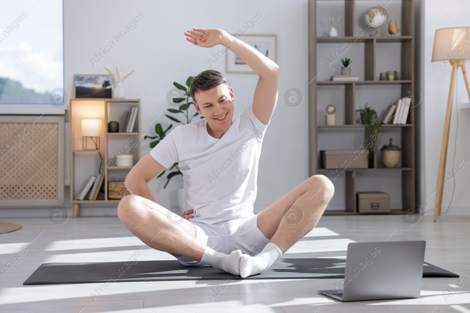 Man having online yoga class via laptop at home Photo of Man having online yoga class via laptop at home