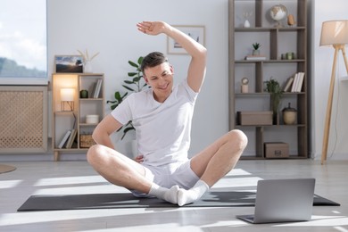 Photo of Man having online yoga class via laptop at home