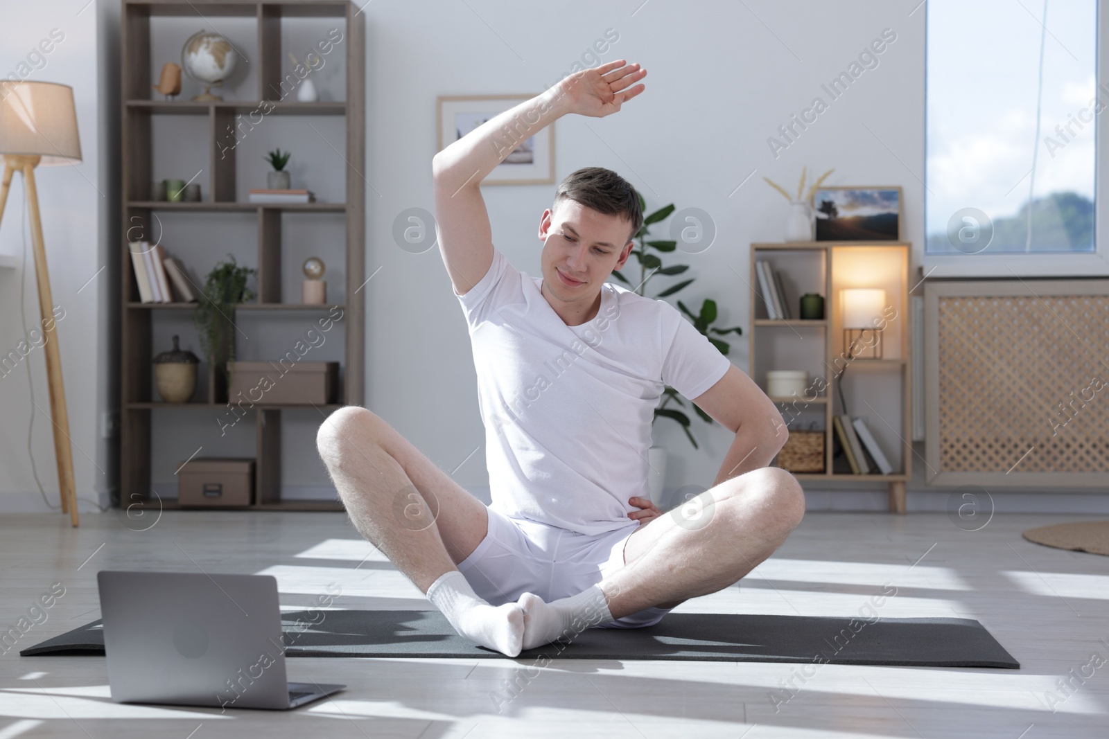 Man having online yoga class via laptop at home Photo of Man having online yoga class via laptop at home