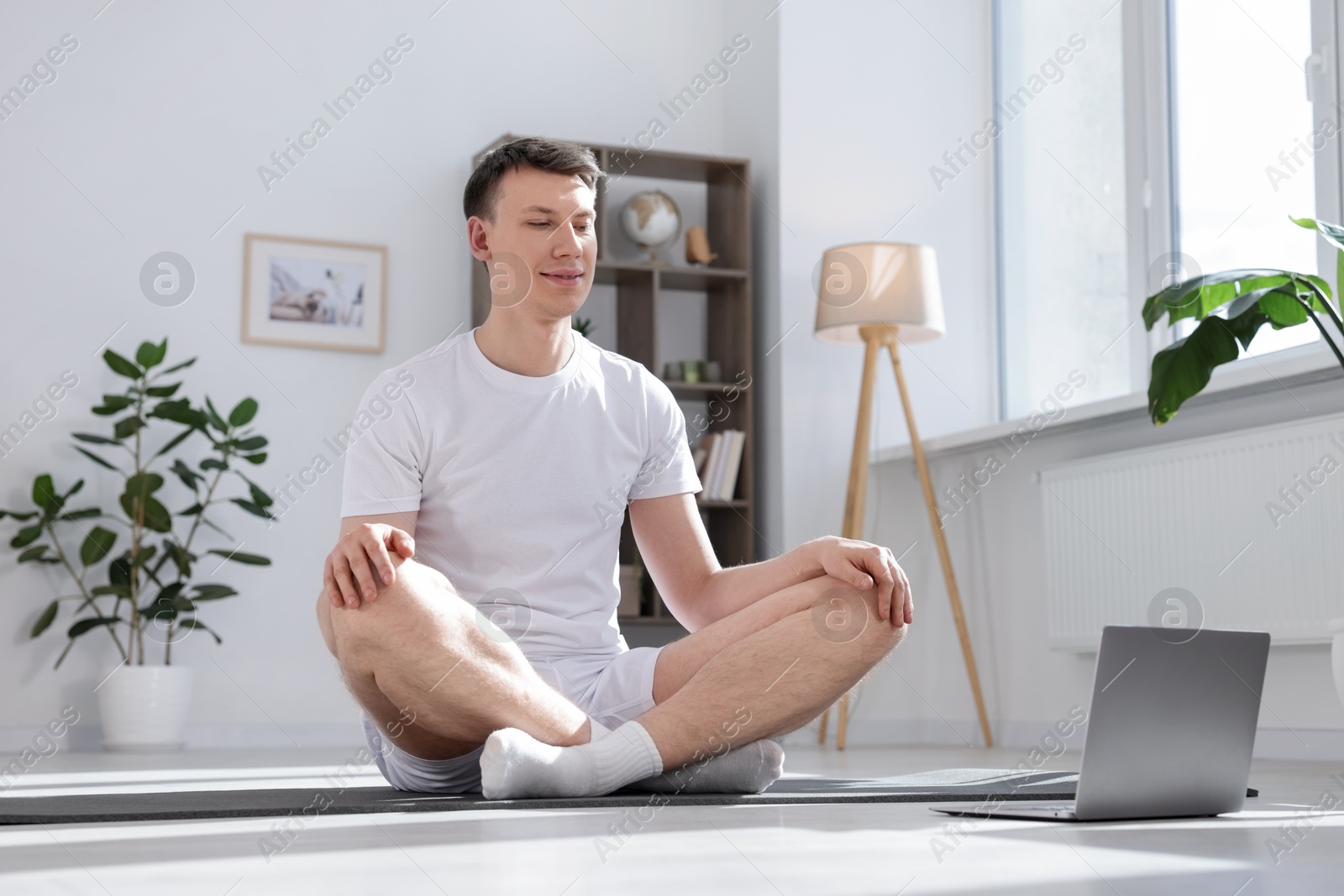 Man having online yoga class via laptop at home. Space for text Photo of Man having online yoga class via laptop at home. Space for text