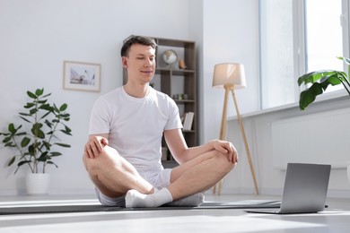Photo of Man having online yoga class via laptop at home. Space for text