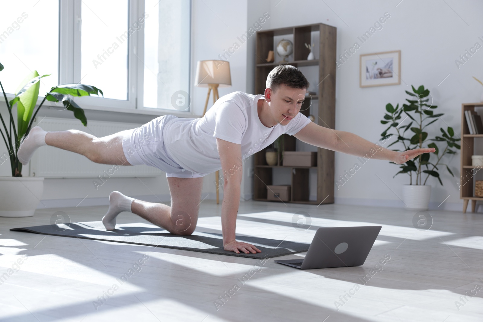 Man having online yoga class via laptop at home Photo of Man having online yoga class via laptop at home