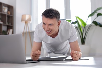 Photo of Man having online yoga class via laptop at home