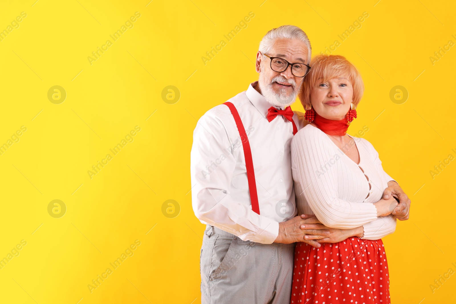 Lovely senior couple together on yellow background, space for text Photo of Lovely senior couple together on yellow background, space for text