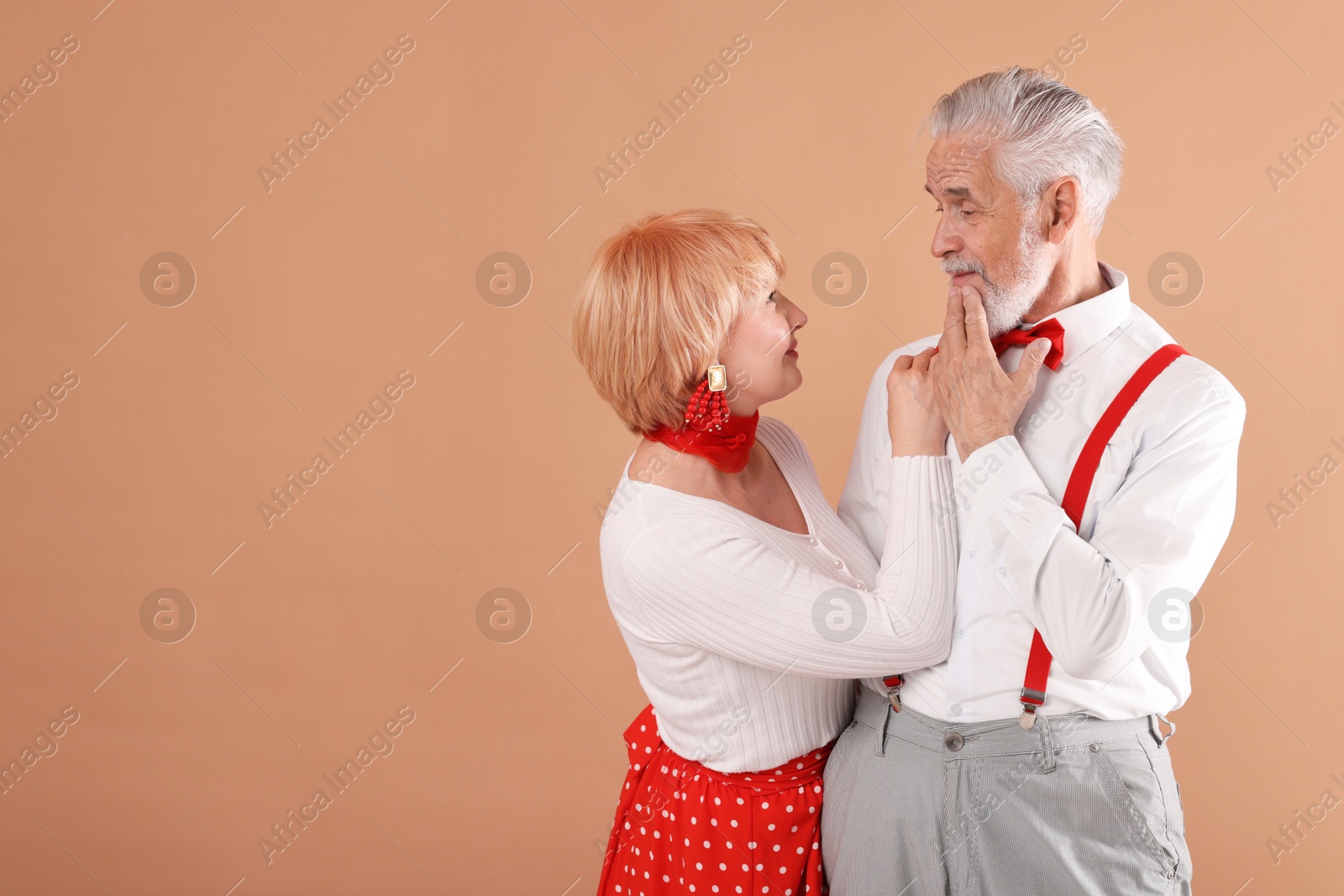 Lovely senior couple together on light brown background, space for text Photo of Lovely senior couple together on light brown background, space for text