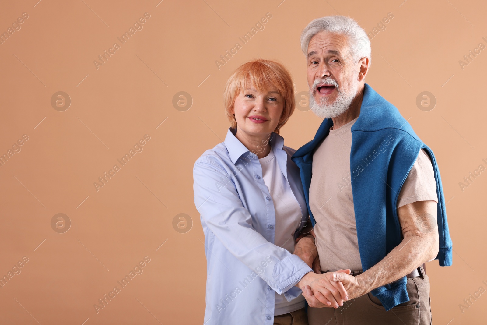 Lovely senior couple together on light brown background, space for text Photo of Lovely senior couple together on light brown background, space for text