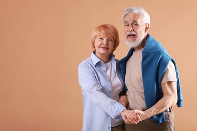 Photo of Lovely senior couple together on light brown background, space for text