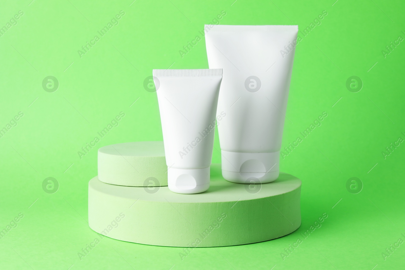 Stylish presentation of moisturizing body cream in tubes on light green background, closeup Photo of Stylish presentation of moisturizing body cream in tubes on light green background, closeup