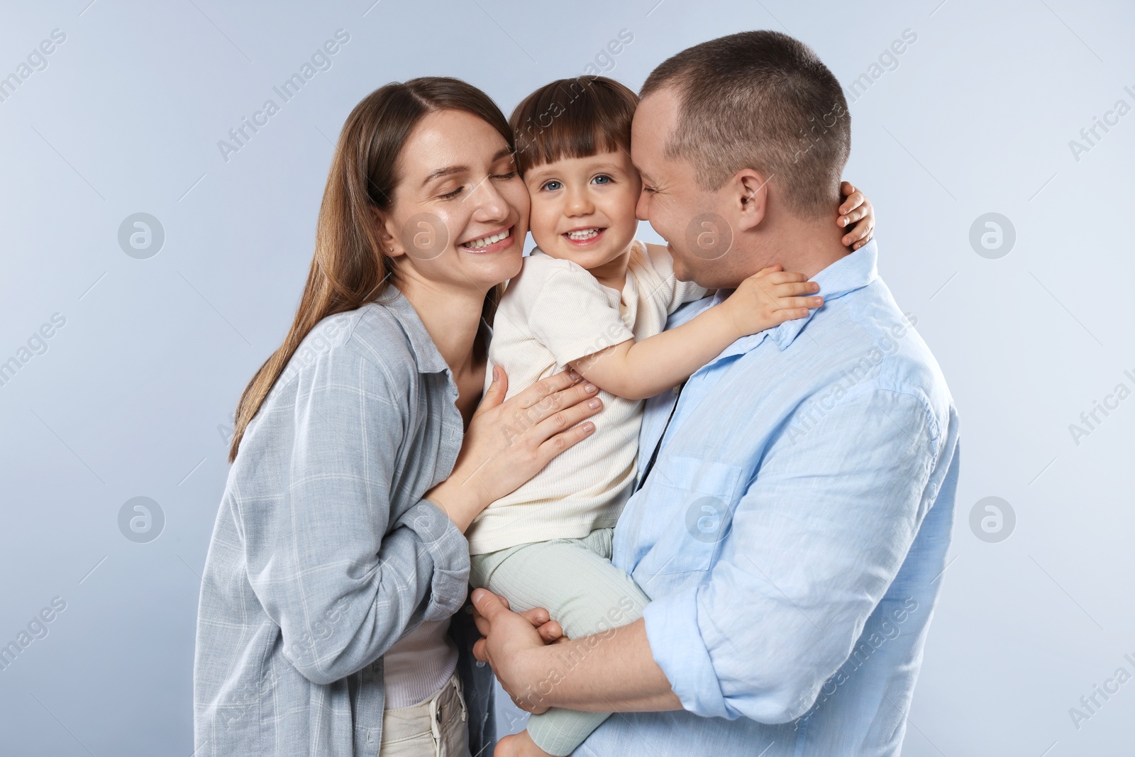 Happy parents and their baby boy on light grey background. Lovely family Photo of Happy parents and their baby boy on light grey background. Lovely family