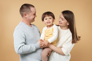 Photo of Happy parents and their baby boy on beige background. Lovely family