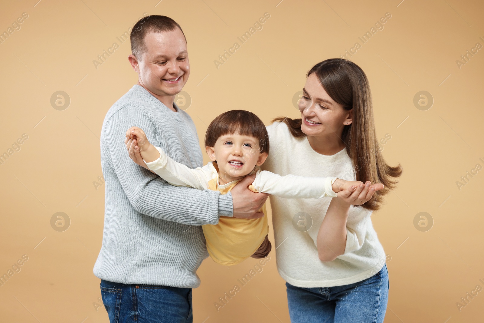 Happy parents and their baby boy on beige background. Lovely family Photo of Happy parents and their baby boy on beige background. Lovely family
