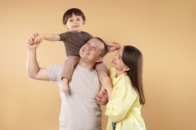 Photo of Happy parents and their baby boy on beige background. Lovely family