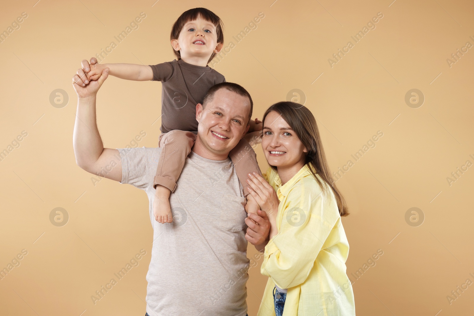 Happy parents and their baby boy on beige background. Lovely family Photo of Happy parents and their baby boy on beige background. Lovely family