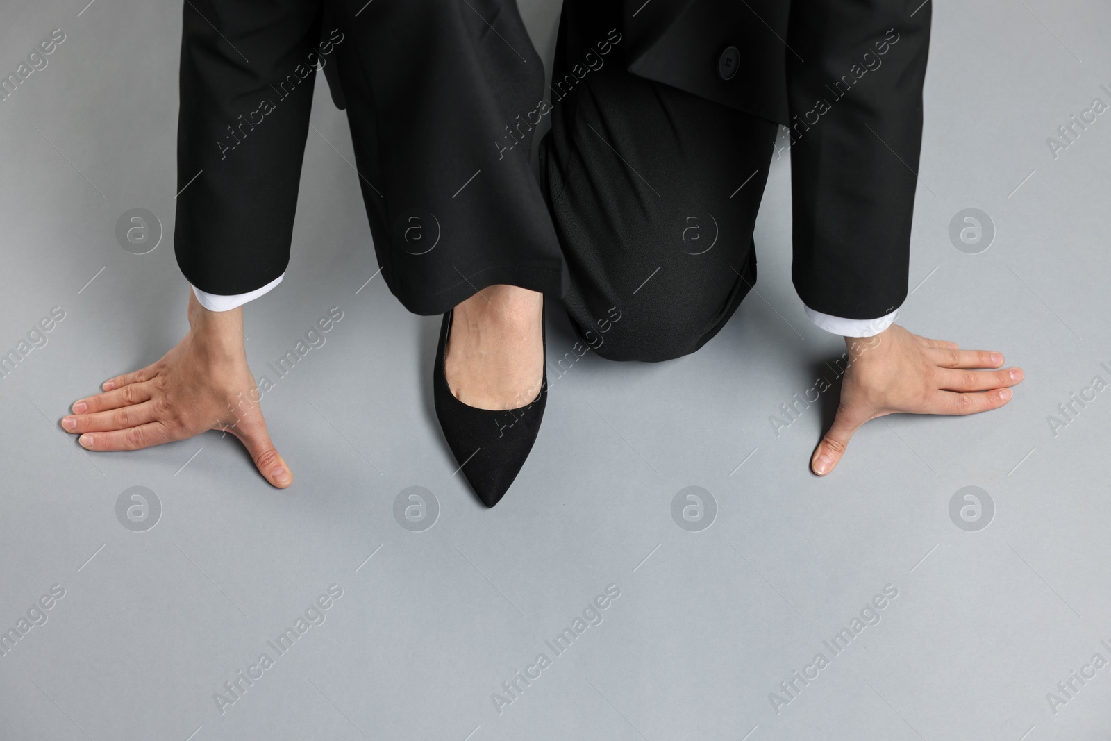 Businesswoman in starting position on gray background, top view. Space for text Photo of Businesswoman in starting position on gray background, top view. Space for text