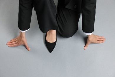 Photo of Businesswoman in starting position on gray background, top view. Space for text