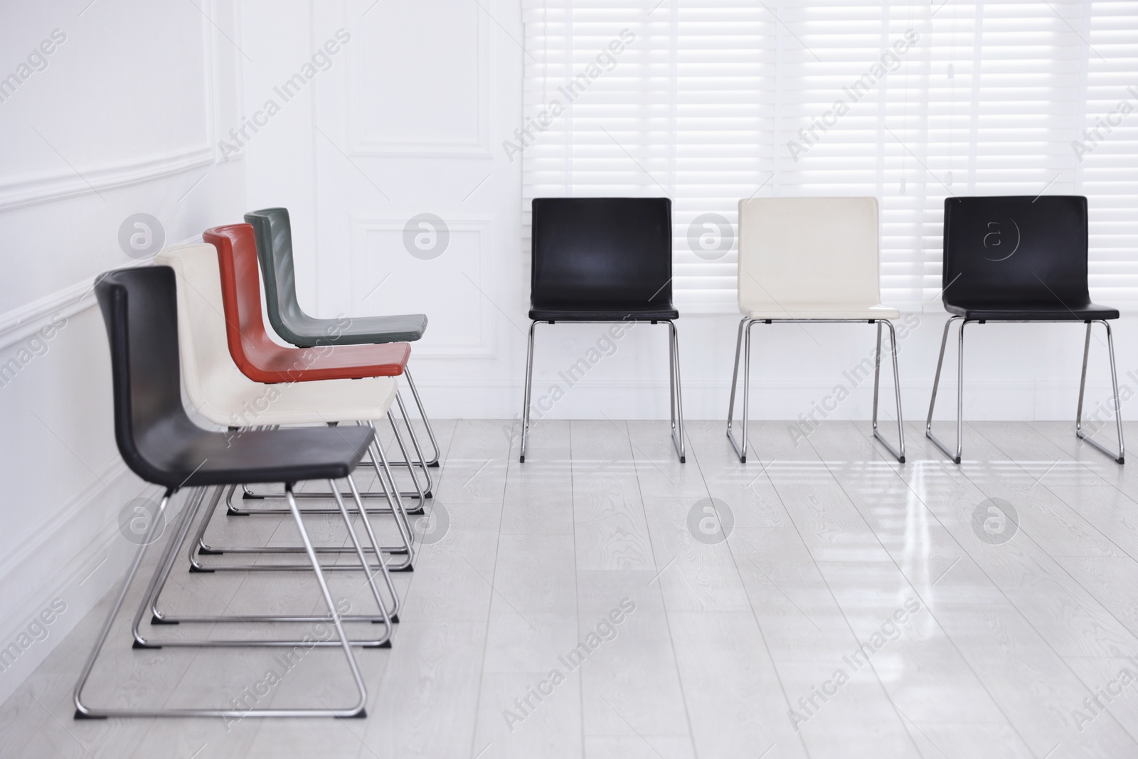Colorful chairs near white wall in waiting room Photo of Colorful chairs near white wall in waiting room