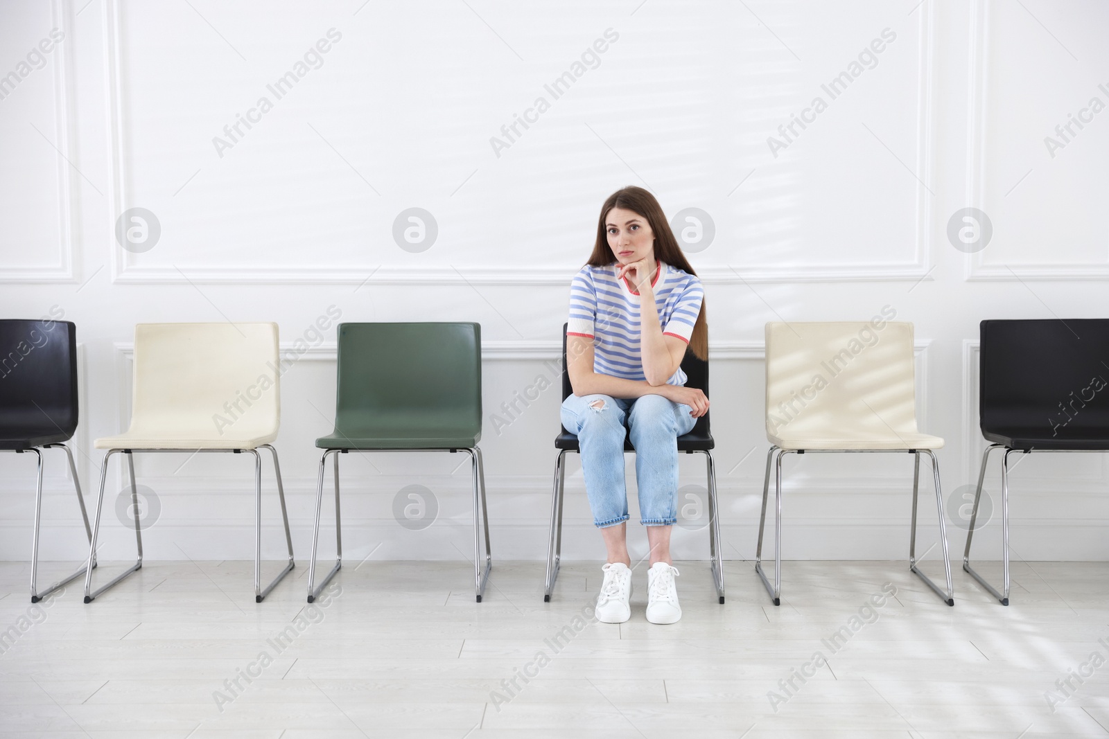 Woman sitting on chair and waiting for appointment indoors Photo of Woman sitting on chair and waiting for appointment indoors