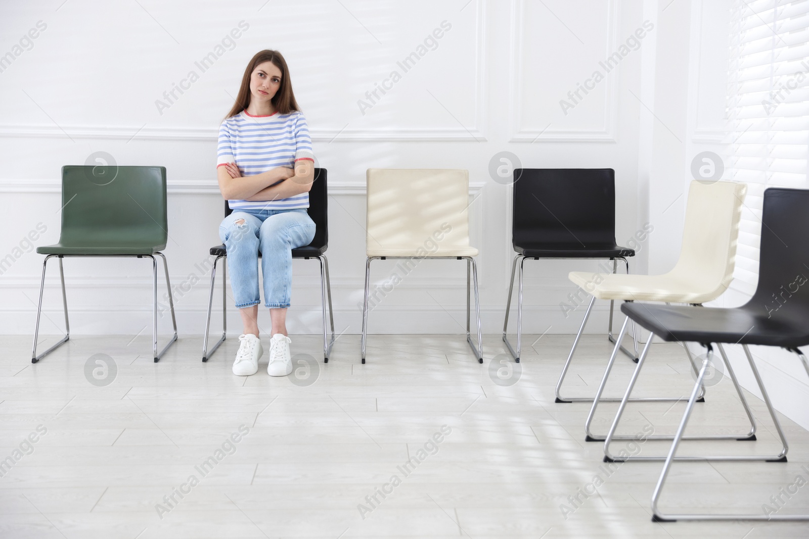 Woman sitting on chair and waiting for appointment indoors Photo of Woman sitting on chair and waiting for appointment indoors