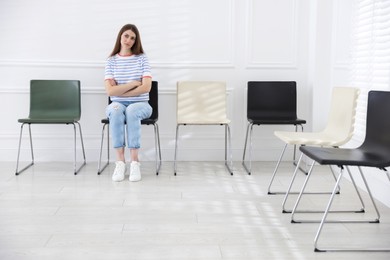 Photo of Woman sitting on chair and waiting for appointment indoors