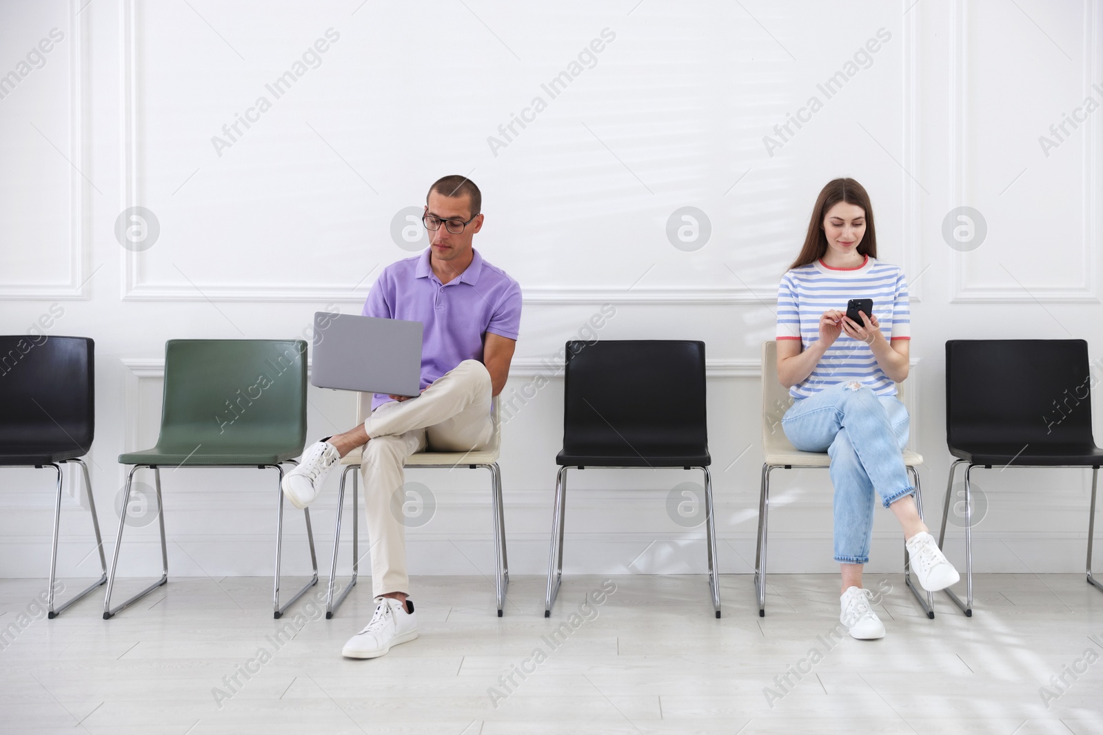 Man and woman waiting for appointment indoors Photo of Man and woman waiting for appointment indoors