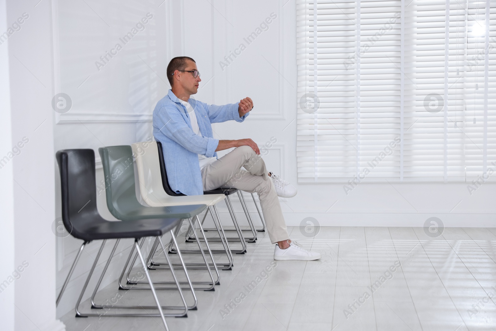 Man looking at wristwatch while waiting for appointment indoors Photo of Man looking at wristwatch while waiting for appointment indoors