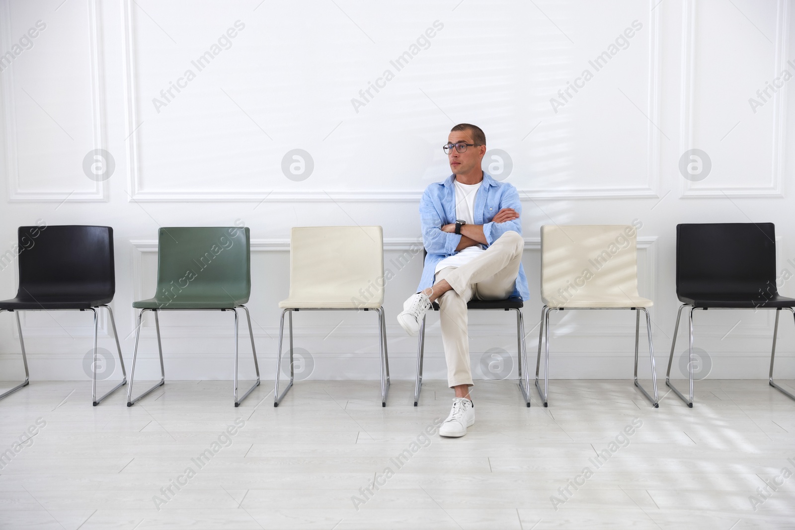 Man sitting on chair and waiting for appointment indoors Photo of Man sitting on chair and waiting for appointment indoors