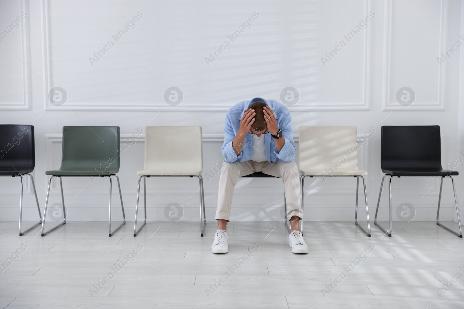 Man sitting on chair and waiting for appointment indoors Photo of Man sitting on chair and waiting for appointment indoors