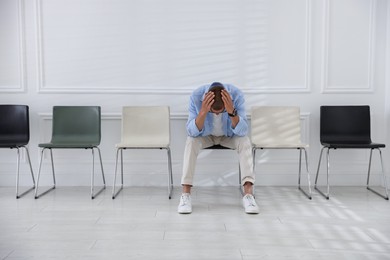 Photo of Man sitting on chair and waiting for appointment indoors