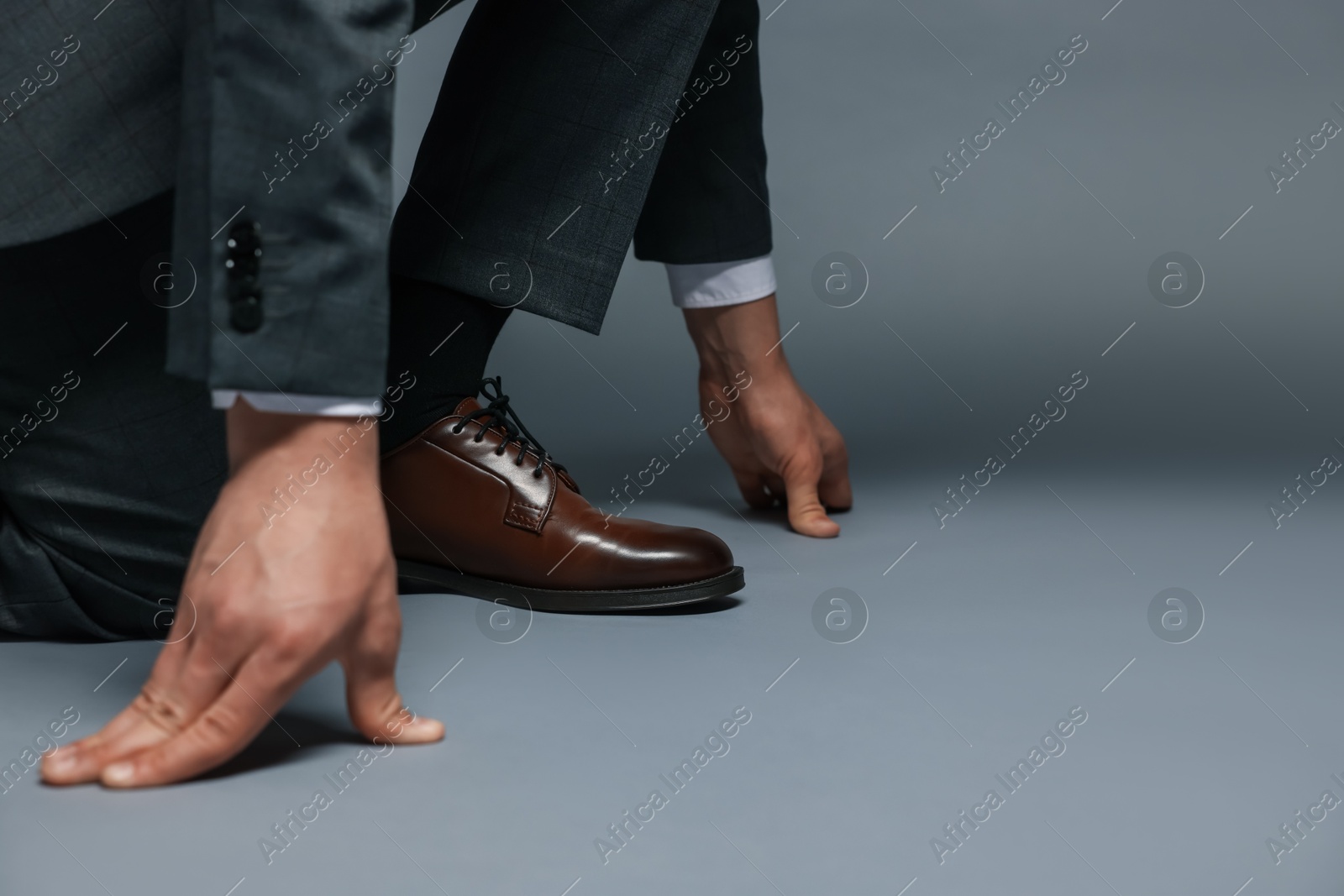Businessman in starting position on gray background, closeup. Space for text Photo of Businessman in starting position on gray background, closeup. Space for text