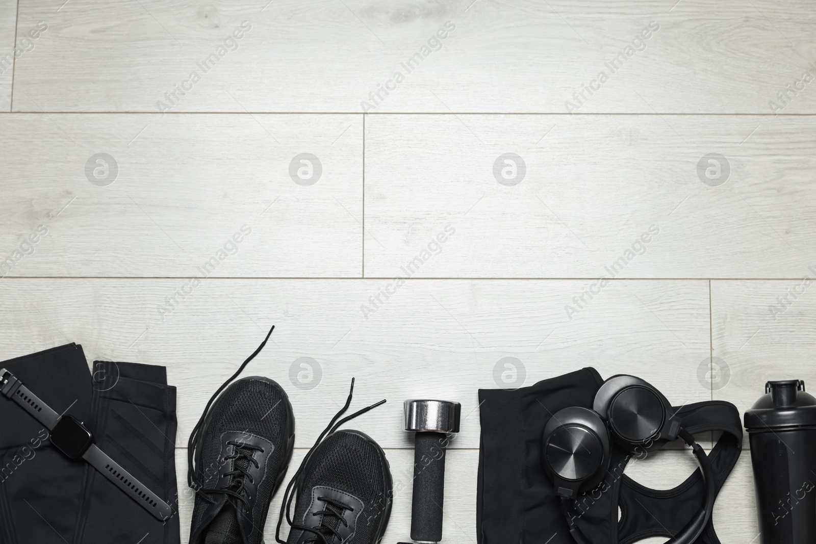 Sportswear, sneakers, wrist watch, headphones and dumbbell on floor, flat lay. Space for text Photo of Sportswear, sneakers, wrist watch, headphones and dumbbell on floor, flat lay. Space for text