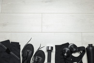 Photo of Sportswear, sneakers, wrist watch, headphones and dumbbell on floor, flat lay. Space for text