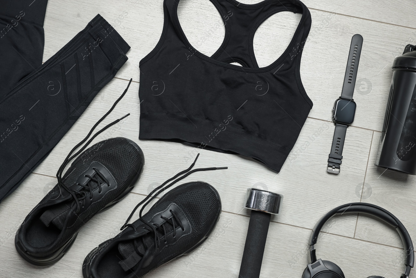 Sportswear, sneakers, wrist watch, headphones and dumbbell on floor, flat lay Photo of Sportswear, sneakers, wrist watch, headphones and dumbbell on floor, flat lay