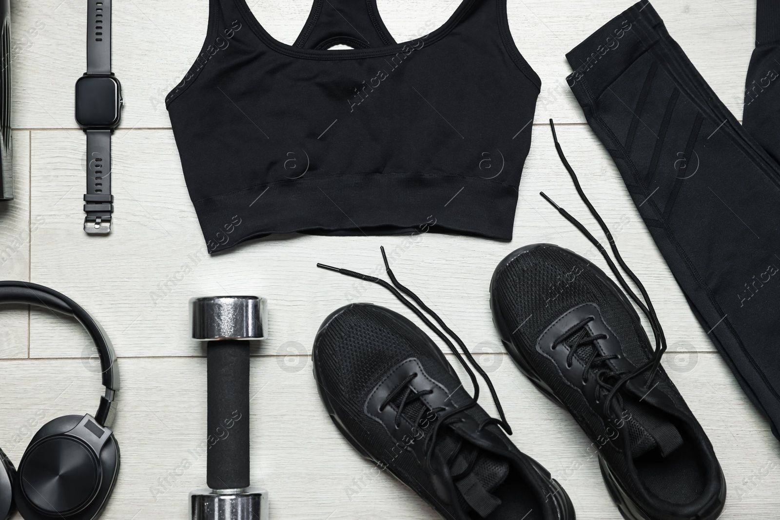 Sportswear, sneakers, wrist watch, headphones and dumbbell on floor, flat lay Photo of Sportswear, sneakers, wrist watch, headphones and dumbbell on floor, flat lay
