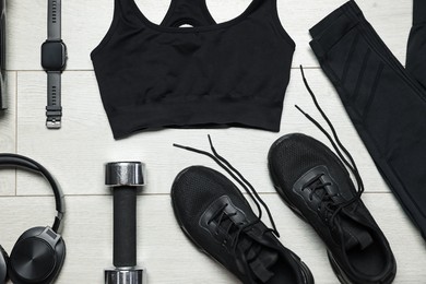 Photo of Sportswear, sneakers, wrist watch, headphones and dumbbell on floor, flat lay