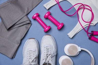 Photo of Sportswear, sneakers, skipping rope, headphones and dumbbells on grey background, flat lay