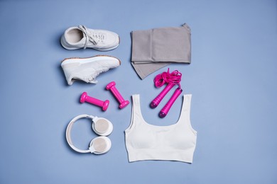 Photo of Sportswear, sneakers, skipping rope, headphones and dumbbells on grey background, flat lay