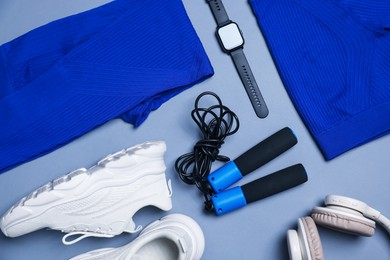 Photo of Sportswear, sneakers, skipping rope and wrist watch on grey background, flat lay